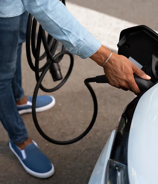 Personne branchant une voiture électrique avec une prise de recharge.